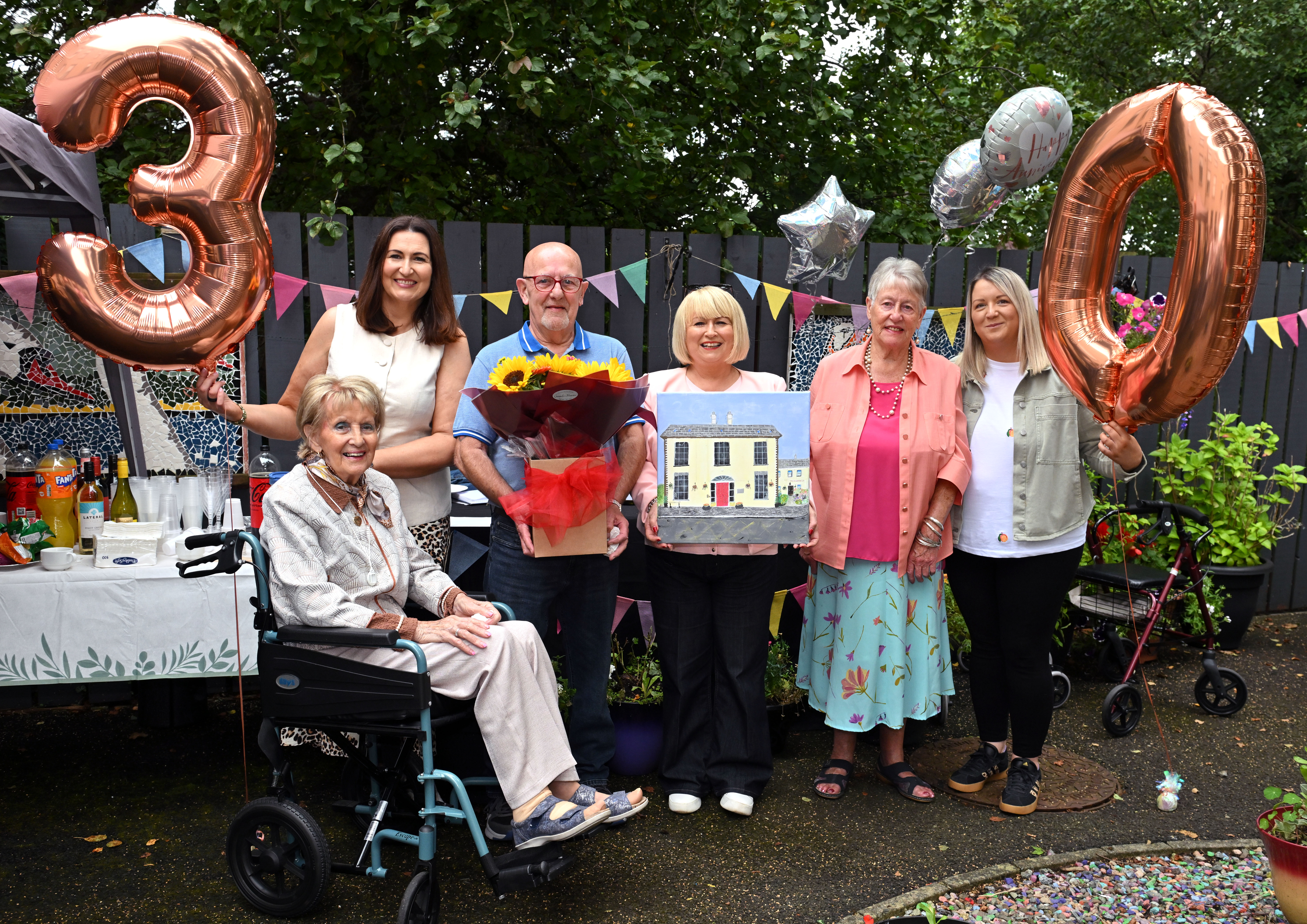 A group of customers and staff at the celebration garden party